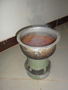 Cooking spaghetti sauce on Chris' kerosene stove. These and charcoal stoves that sit on the floor are the typical cooking tool. 